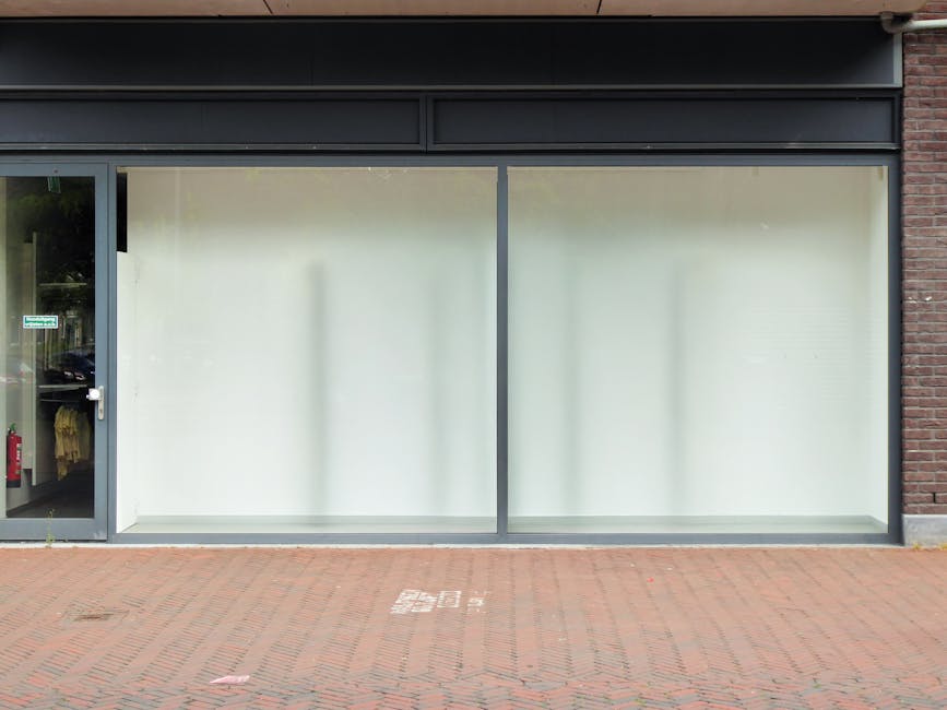 A busy street scene on Bromley High Street featuring a variety of commercial buildings, including shops with large display windows and ornate brick facades. The road has clearly marked pedestrian cros